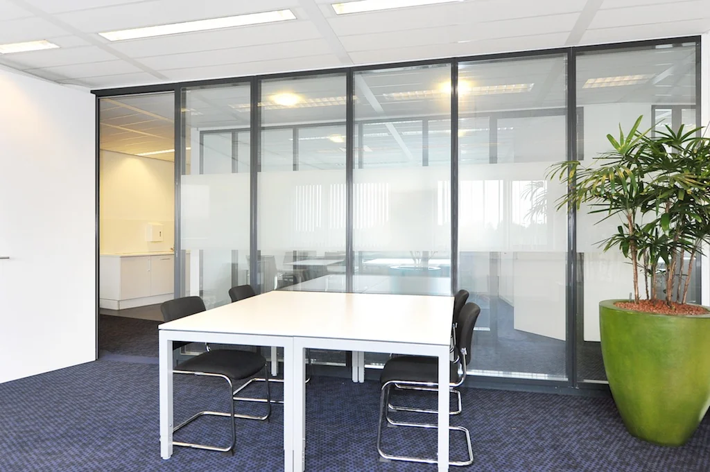 Vergaderruimte aan de Laan van s-Gravenmade met glazen wanden, moderne inrichting en een grote kamerplant.